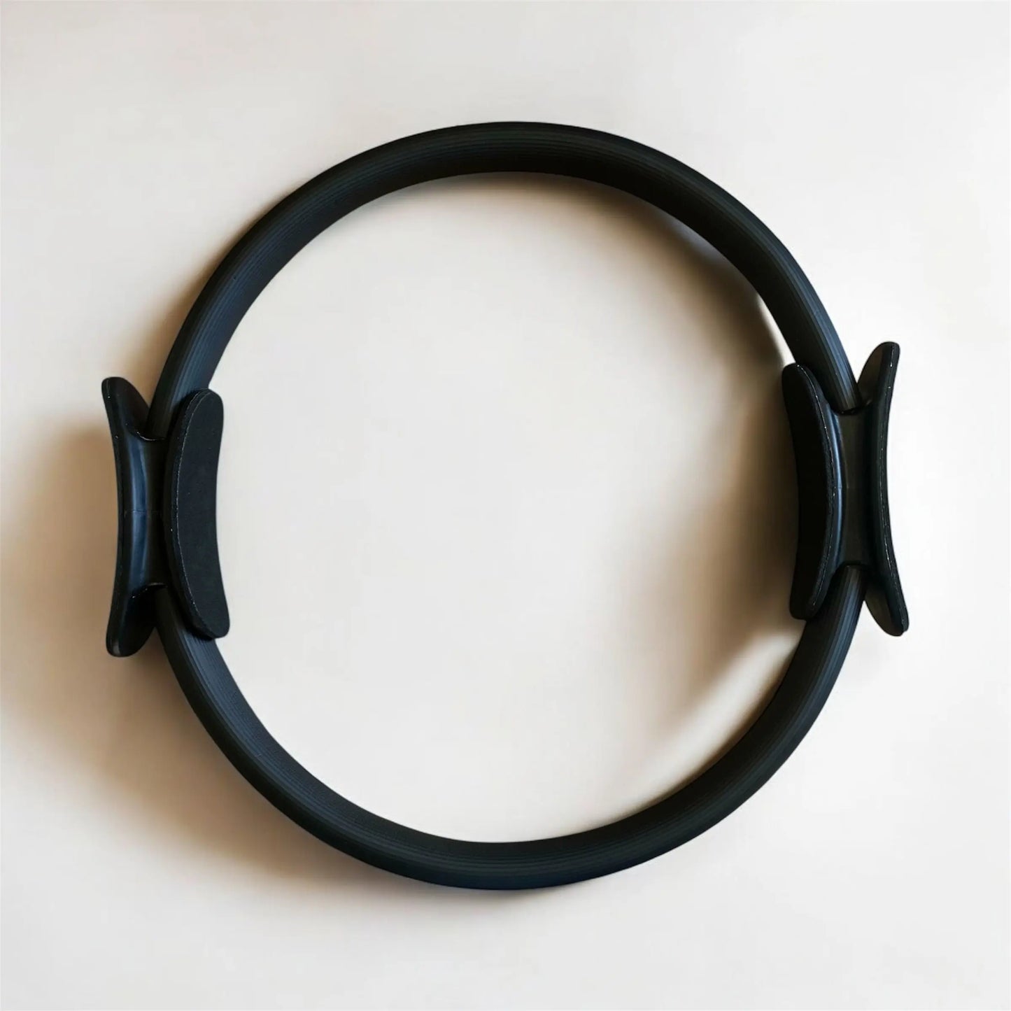 Anneau de pilates noir, idéal pour renforcer bras et jambes dans les exercices de pilates.